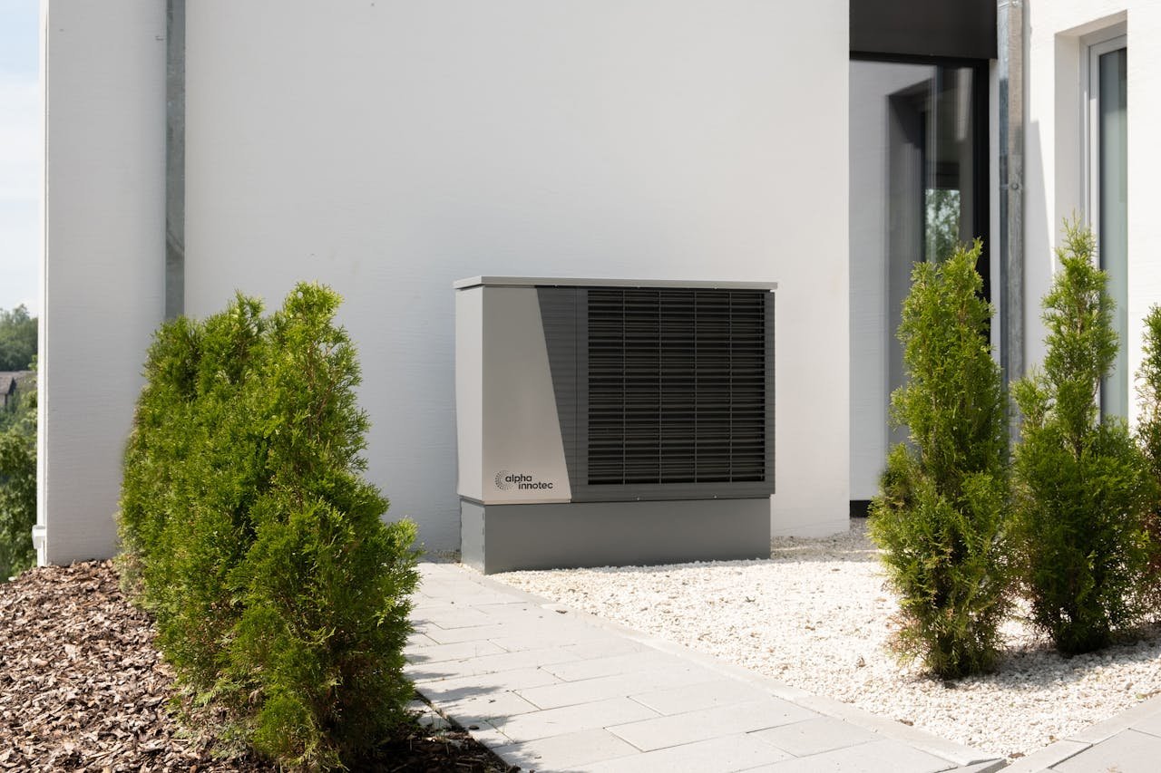 Outdoor air conditioner unit on a modern building surrounded by greenery and landscaping.